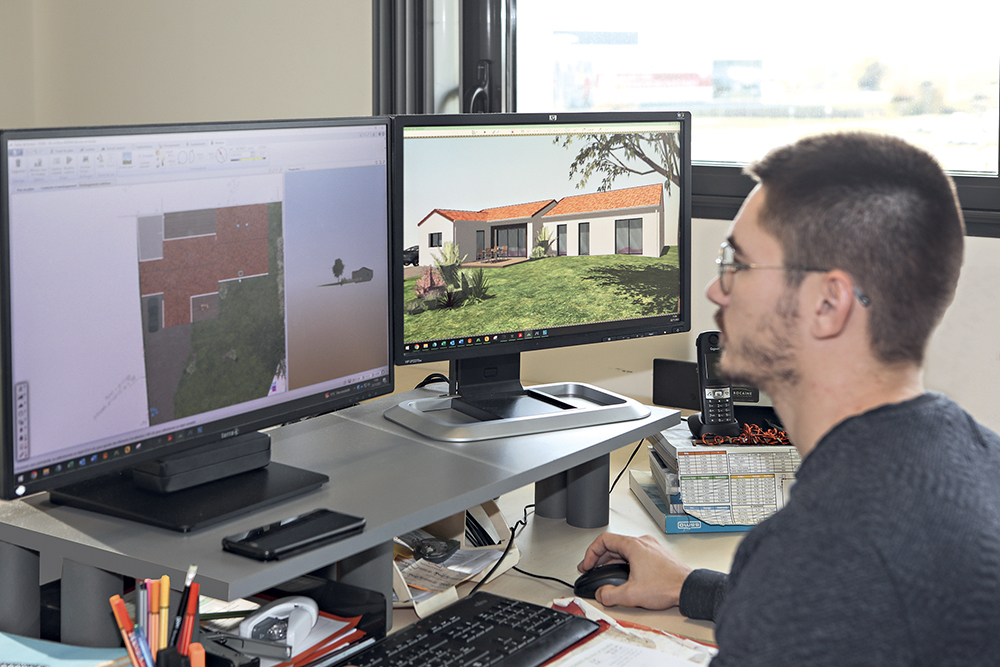 Un homme face à un ordinateur avec des plans d'une maison La Bocaine