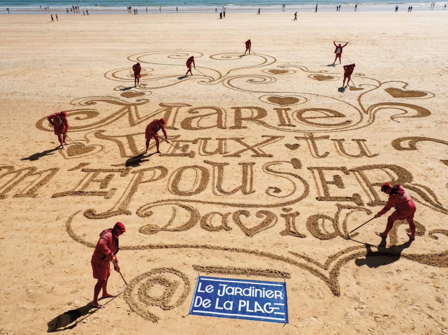 "Marie veux tu m'épouser ? David" écrit sur le sable.