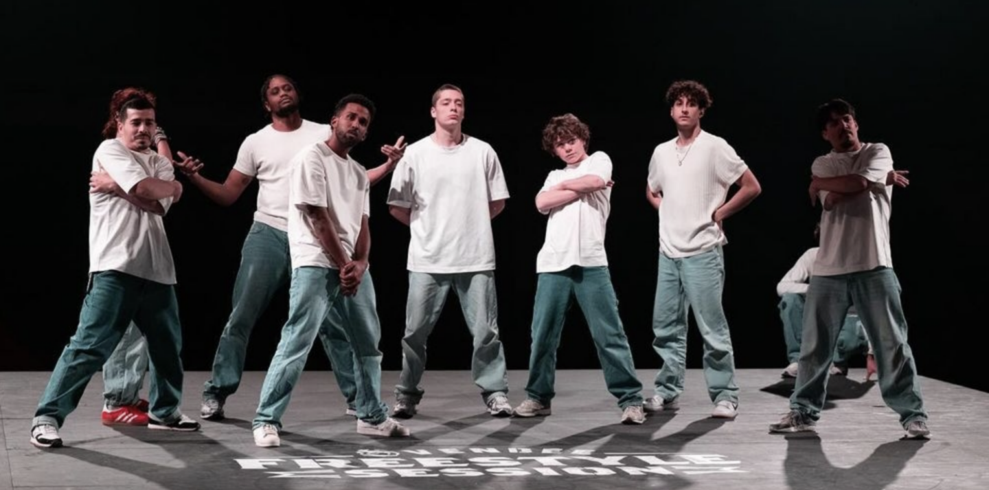 Un groupe de huit hommes vêtus de t-shirts blancs et de pantalons bleu verdâtre, menés par Ruben Boisseleau, se tient avec assurance sur une scène, prenant des poses hip-hop sous un éclairage dramatique. Sur la scène est écrit Freestyle. - Édition Offset 5 (Partenaire de votre communication locale en Vendée)