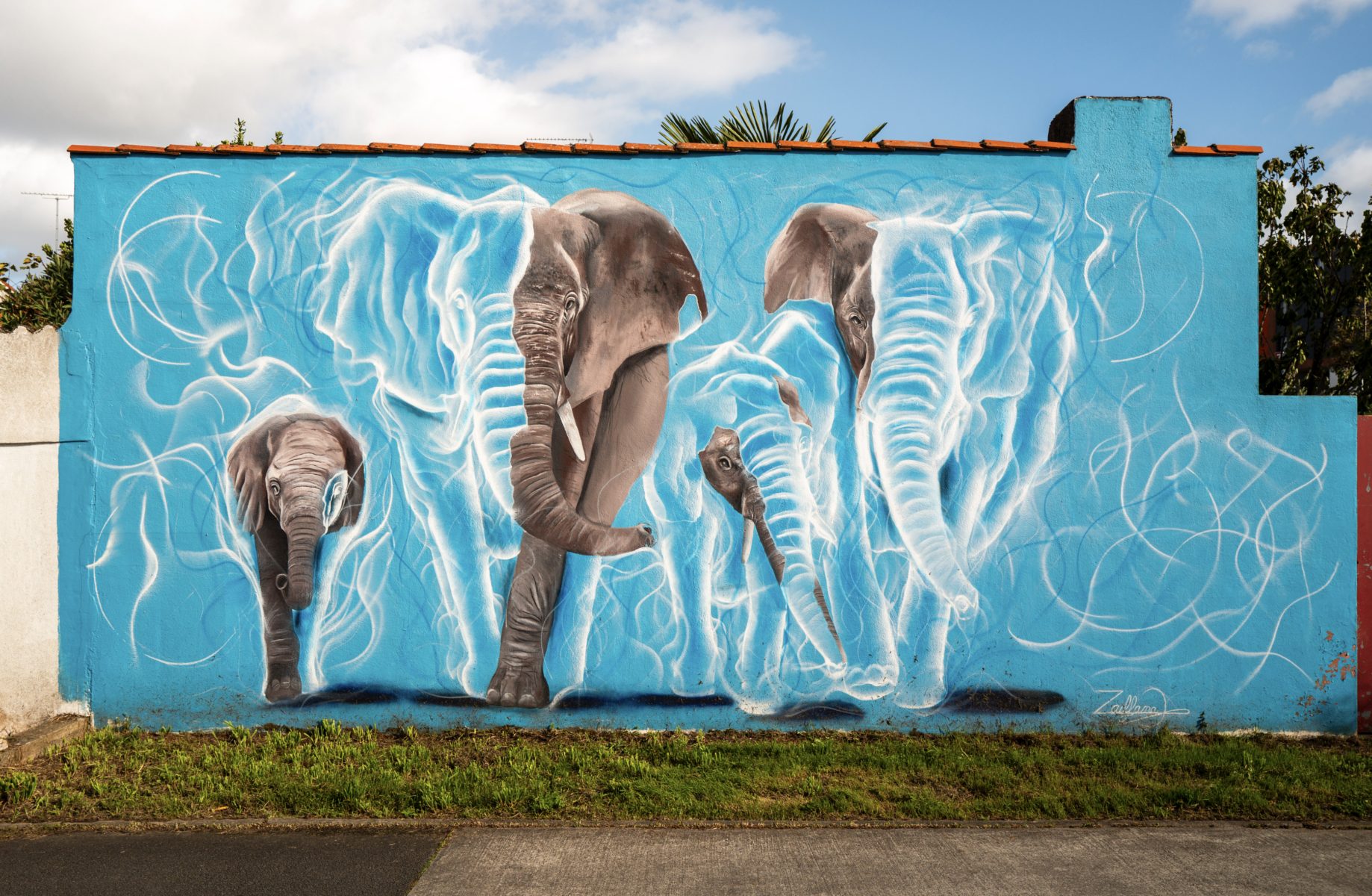 Une peinture murale vibrante de Simon Boisliveau sur un mur bleu représente quatre éléphants délimités par des lignes blanches lumineuses, avec des arbres et le ciel en arrière-plan. L'œuvre présente des détails réalistes et dynamiques des éléphants dans différentes poses. - Édition Offset 5 (Partenaire de votre communication locale en Vendée)