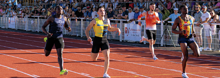 Quatre hommes sprintent sur une piste de La Roche-sur-Yon ville active et sportive, avec une foule de spectateurs en arrière-plan. Les coureurs s'approchent de la ligne d'arrivée, trois devant et un légèrement derrière. - Édition Offset 5 (Partenaire de votre communication locale en Vendée)