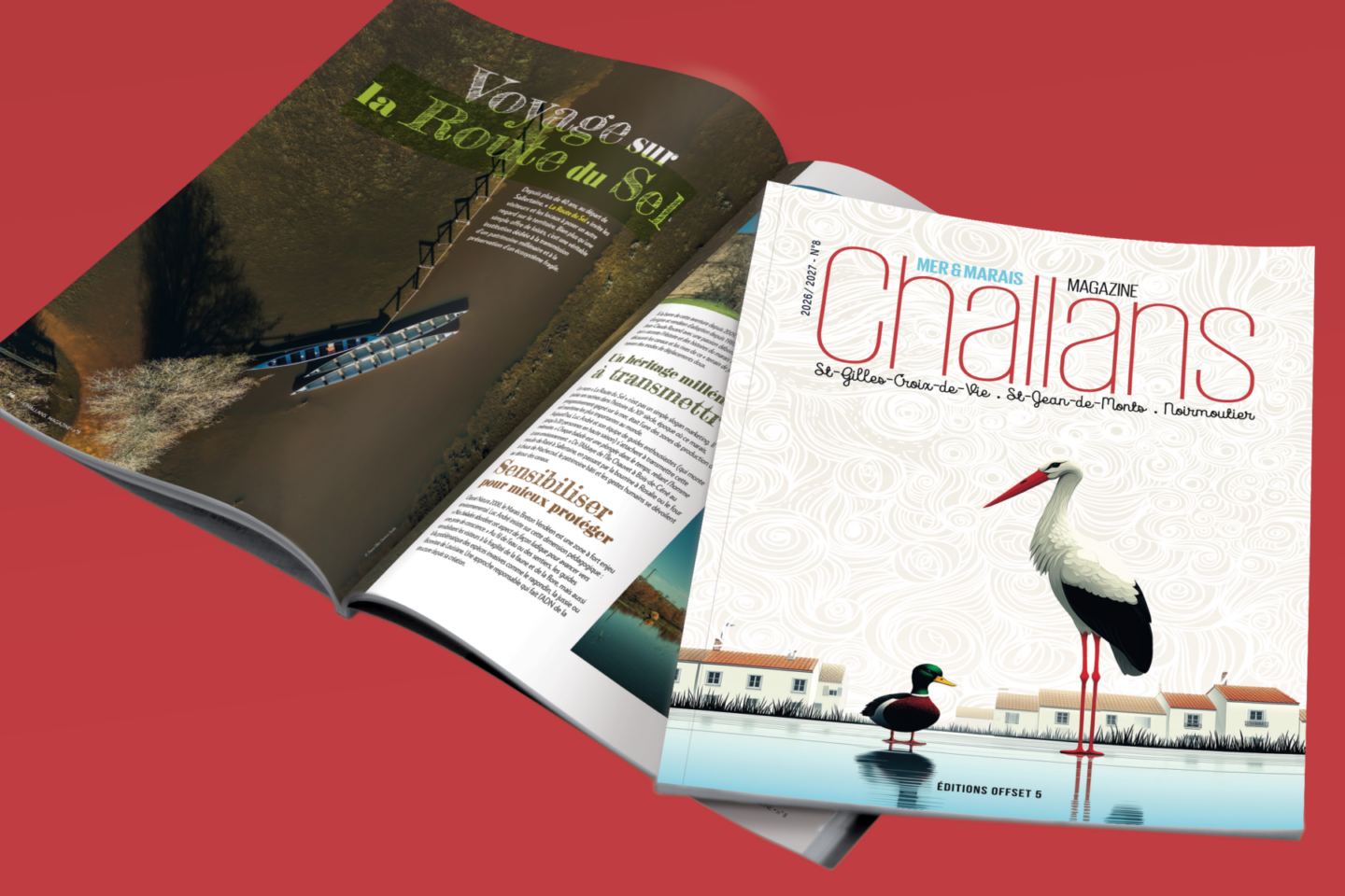 Deux magazines sur une surface rouge : l'un ouvert, révélant une photo aérienne d'un bateau sur l'eau ; l'autre fermé, présentant une cigogne illustrée et des toits sur la couverture blanche du magazine Challans. - Édition Offset 5 (Partenaire de votre communication locale en Vendée)