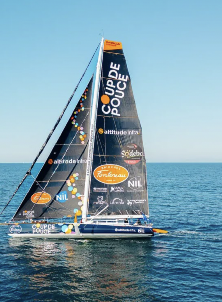 Un voilier bleu et blanc dont la grande voile est recouverte de logos de sponsors colorés, dont "COUP DE POUCE" et "2 Mains 4 Cornes", navigue sur les eaux calmes et bleues de l'océan sous un ciel clair. - Édition Offset 5 (Partenaire de votre communication locale en Vendée)